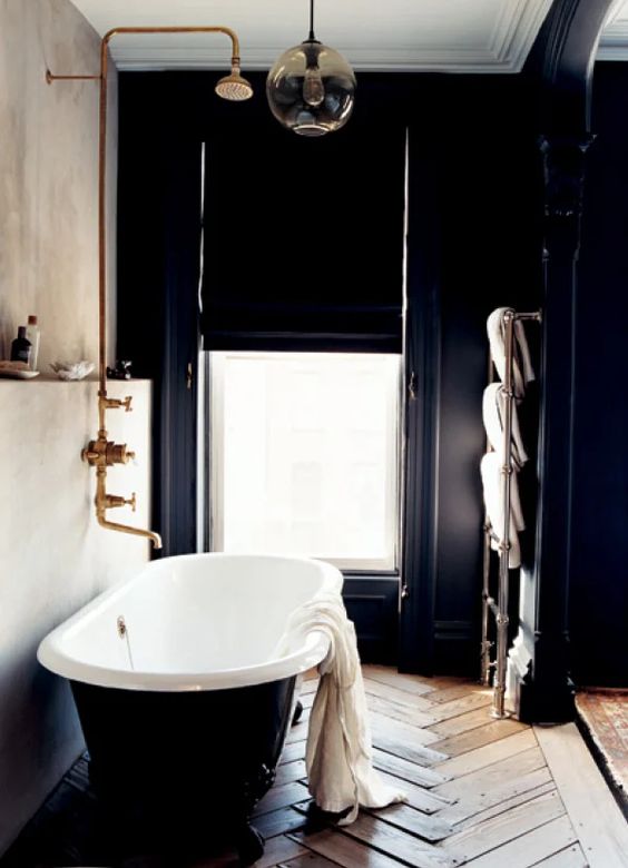 a refined vintage bathroom with a wooden floor, a concrete and a black wood wall, a window with a black curtain and a black clawfoot tub