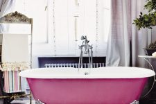 05 a beautiful bathroom with a blush star print tile floor, a bright pink bathtub, lilac curtains, a stand for towels and potted greenery