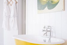 16 a pure white bathroom with shiplap walls, a bold yellow clawfoot bathtub, a pretty artwork and neutral textiles is cool
