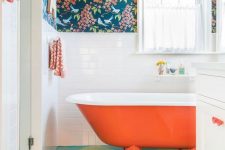 18 a colorful bathroom with dark floral wallpaper, white subway tiles, an orange bathtub, a bright green and turquoise floor and white textiles