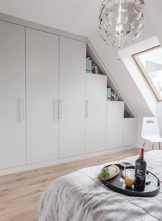 A Scandinavian bedroom with a skylight, a built in storage unit with open shelves, a bed with neutral bedding