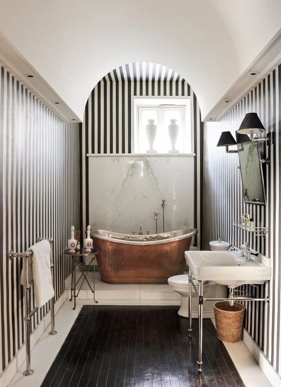 A chic vintage inspired monochromatic bathroom with a copper bathtub that adds warmth and color to the space