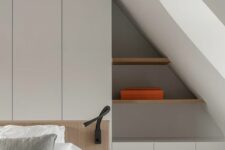 a minimalist attic bedroom with a white storage unit built into the wall, with built-in shelves and cabinets is a smart solution