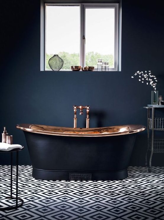 a modern luxurious bathroom with black walls, a mosaic tile floor, a copper and black tub and elegant furniture