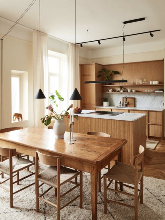 a modern stained kitchen with a white marble backsplash and countertops, a matching kitchen island, a wooden dining set with woven chairs