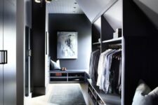 a moody sloped closet with open storage compartments and benches, with rugs and decor plus an elegant chandelier is lovely