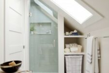 a neutral attic bathroom with a shower space done with aqua tiles, penny marble tiles on the floor and a large skylight