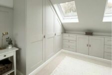 a neutral attic closet with built-in wardrobes, cabinets and drawers, skylights and rugs for more coziness is a cool space