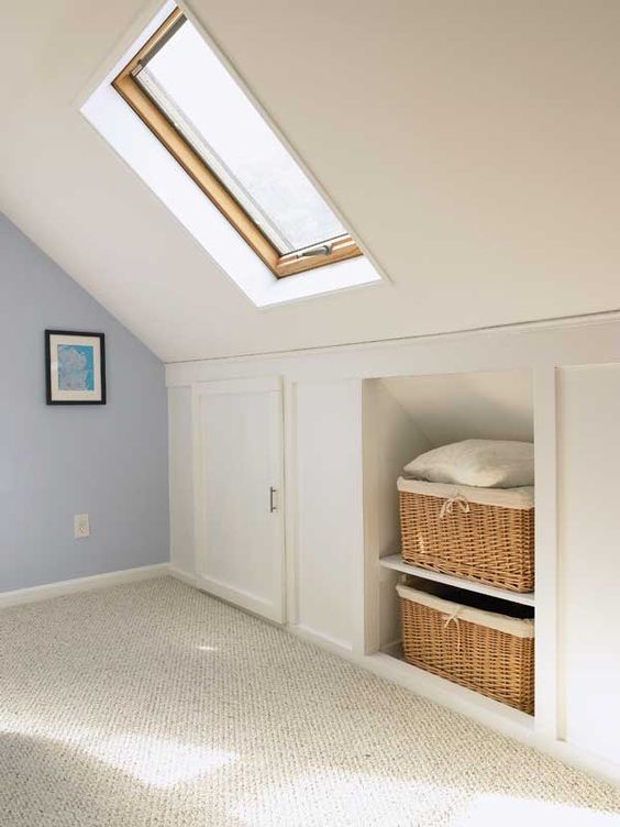 A pretty neutral attic room with built in storage   baskets for storage and storage compartments with doors is amazing