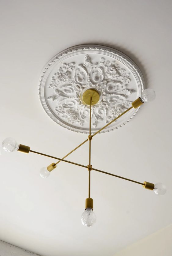 A refined white ceiling medallion to accent a stylish mid century modern gold ray chandelier with bulbs for a stylish modern room
