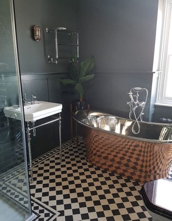 A retro inspired black and white bathroom spruced up with a gorgeous vintage copper tub and a potted plant