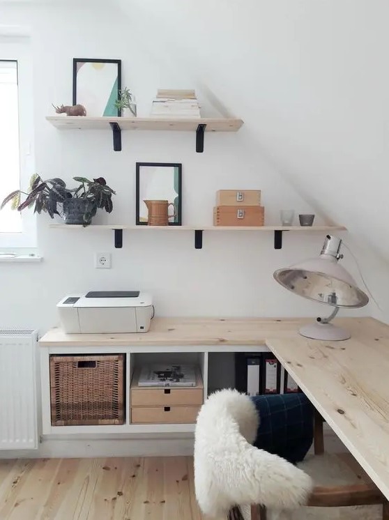 A small attic Nordic home office with floating desk with storage, wall mounted shelves, cool lamps and a comfy chair