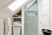 a small attic bathroom with skylights and a shower space, with built-in attic storage and a sink is a smart use of space