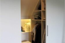 a small attic closet with open storage compartments and niches, with drawers and shelves, built-in lights and sliding doors