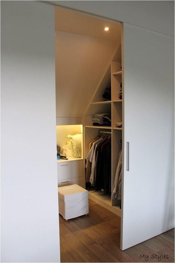 A small attic closet with open storage compartments and niches, with drawers and shelves, built in lights and sliding doors