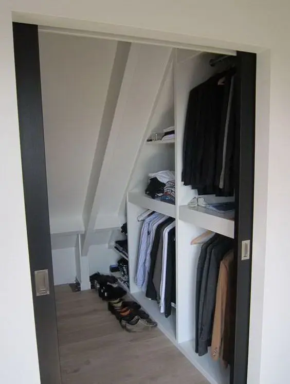 A small attic walk in closet with open storage compartments and shelves is a cool solution that features a lot of storage space