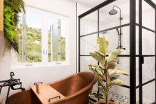 a stylish bathroom with a shower enclosed in glass, a black and white floor, a copper bathtub and lots of greenery is wow