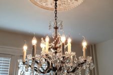 a white ceiling medallion paired with a crystal chandelier, with candles and crystals hanging down for adding vintage chic to the space