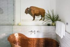 a white modern farmhouse bathroom with skinny tiles, a glass enclosed shower space, a copper bathtub of a very peculiar shape