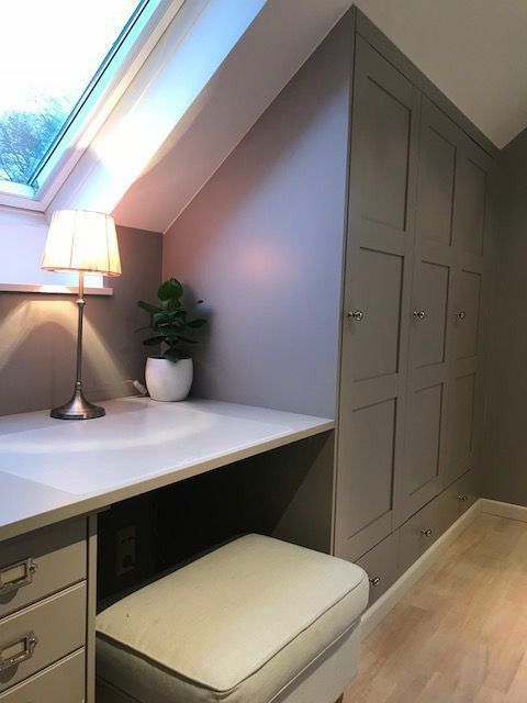 An attic closet with a graphite grey built in wardrobe, a built in vanity and a stool plus some lights