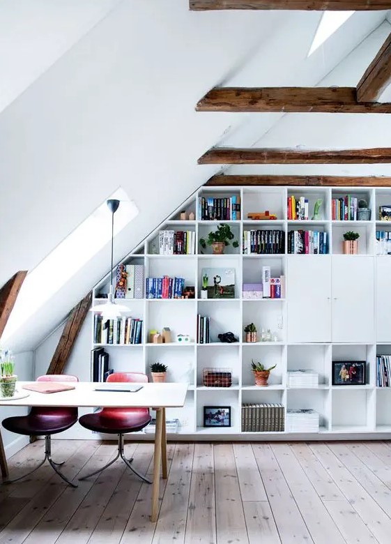 an attic home office with stained wooden beams, a built-in storage unit, a desk, pink and purple chairs and some skylights to give more natural light