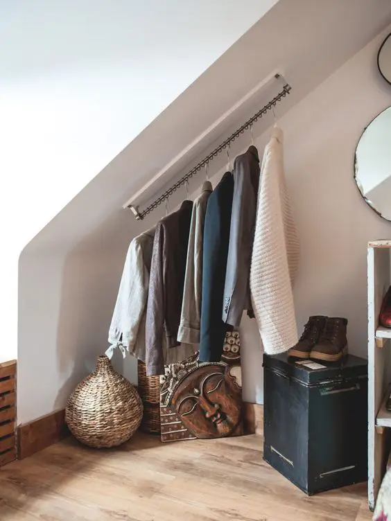 an attic nook with railing for the clothes, some decor, a chest and some mirrors is a great space for an attic home