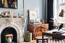 an eclectic space with a vintage non-working fireplace, a large industrial dining table, a vintage stained file cabinet, layered rugs, artworks and books