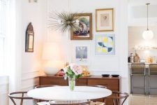 an elegant mid-century modern dining nook with a stained credenza, a round table and stained chairs, a gallery wall and a sunburst chandelier