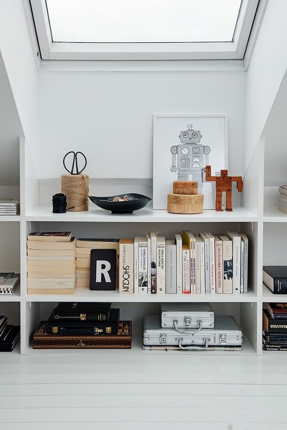 Elegant open bookshelves under the roof are a veyr stylish and chic idea for a modern attic   display all the objects you want