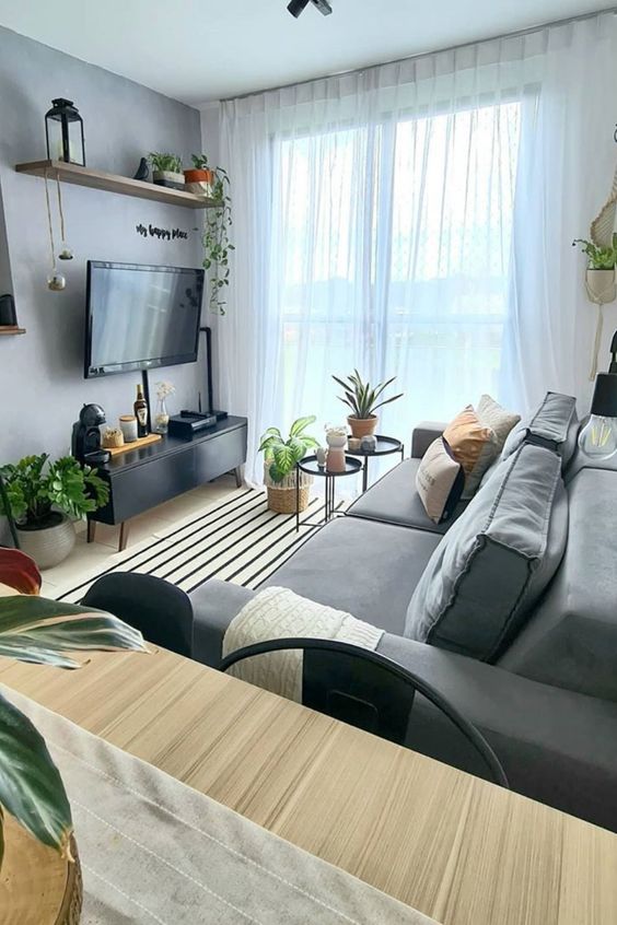 a stylish small Scandi living room with a wall-mounted TV and all the wires hidden inside black wire tubes attached to the wall