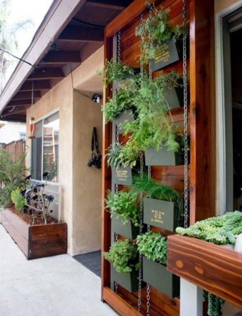 a vertical garden on chain, with blackened metal planters with herbs and names on them is a smart solution for a space with no garden
