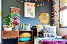 02 a bright kid’s room with a black wall, colorful pompom garlands, pillows, bedding and a rug is extra bold