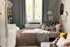 09 a neutral small kid’s bedroom with a metal bed with pastel bedding, a sofa with pillows, a white dresser and a wardrobe