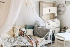 13 a shabby chic meets boho kid’s room with neutral walls, white vintage furniture, pretty bright bedding and pillows and a canopy over the bed
