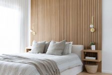 14 a contemporary neutral bedroom with a wood slat accent wall, a neutral upholstered bed with neutral bedding, floating nightstands