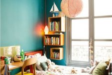 15 a small and colorful kids’ room with a stained bed with printed bedding, emerald walls, bookshelves, a shared desk and colorful chairs