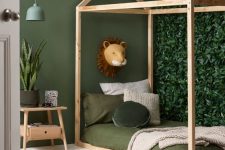 17 a small jungle kids’ room with a faux greenery accent wall, a house-shaped bed with green bedding, a jute rug and a nightstand with plants