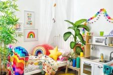 24 a super bold kid’s room with rainbow color garlands, matching bedding, blankets and pillows, a colorful rug and artworks