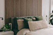 35 a mid-century modern meets Scandinavian bedroom with a wood slat accent wall, a grey upholstered bed with neutral bedding, white nightstands and lots of potted plants