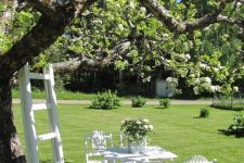 36 a relaxed white dining spot around the tree, with white blooms, a ladder next to the tree is a lovely space for summer