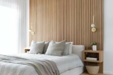 a contemporary neutral bedroom with a wood slat accent wall, a neutral upholstered bed with neutral bedding, floating nightstands