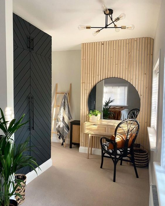 A cool entryway with a built in wardrobe, a wood slat accent wall, a round mirror, a cane console table and a black chair