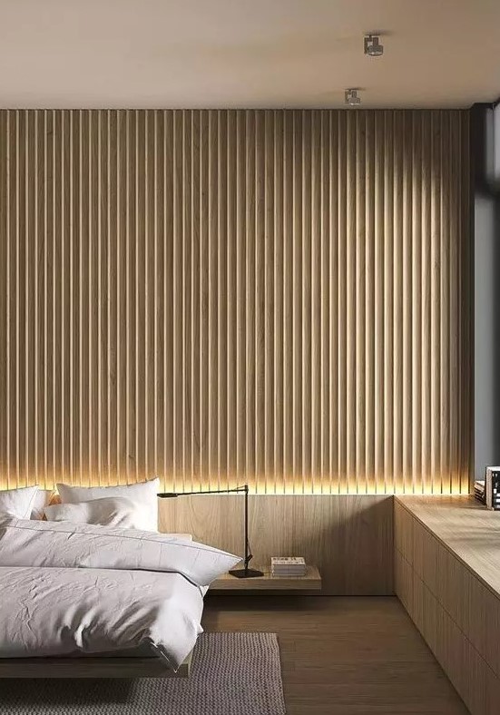 A minimalist bedroom with a light stained wood slat accent wall, a floating bed and nightstand, a built in windowsill storage unit