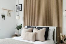 a modern bedroom with a wood slat accent wall, a bed with neutral bedding, nightstands and some lovely decor