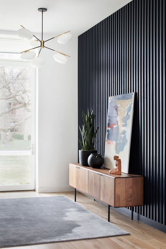 a navy wood slat accent wall, a stained credenza with beautiful decor and a dip-dyed rug for a beautiful space