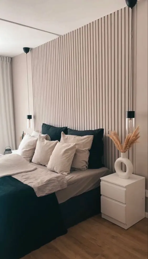 a neutral bedroom with neutral walls and a wood slat one, a bed with green and grey bedding, white nightstands and cool sconces