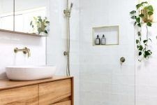 a small and welcoming modern bathroom with white and grey tiles, a catchy floating vanity, a mirror cabinet and touches of brass