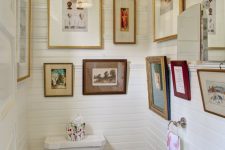 a small neutral mudroom with planked walls, white appliances, vintage gallery walls and a pendant lamp and printed towels
