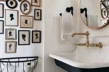 a white farmhouse bathroom with planked walls, a navy wall-mounted sink, a vintage silhouette gallery wall and vintage fixtures