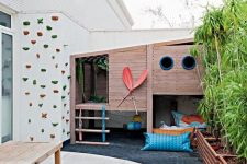 04 a kids’ backyard with a house, a lounge zone with lots of pillows and a climbing wall, a dining set of wood